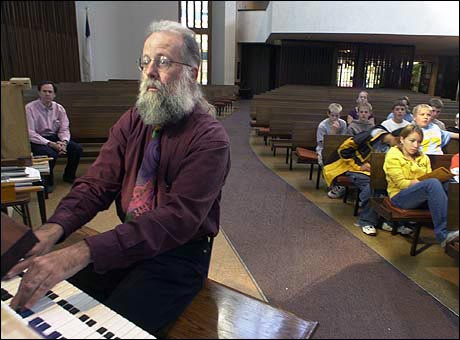 Michael Barone demonstrates how an organ is played, while students look on.