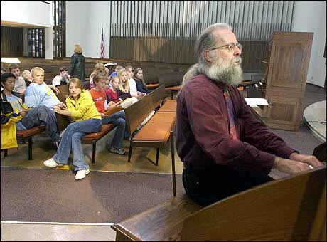 Michael Barone demonstrates how an organ is played, while students look on.